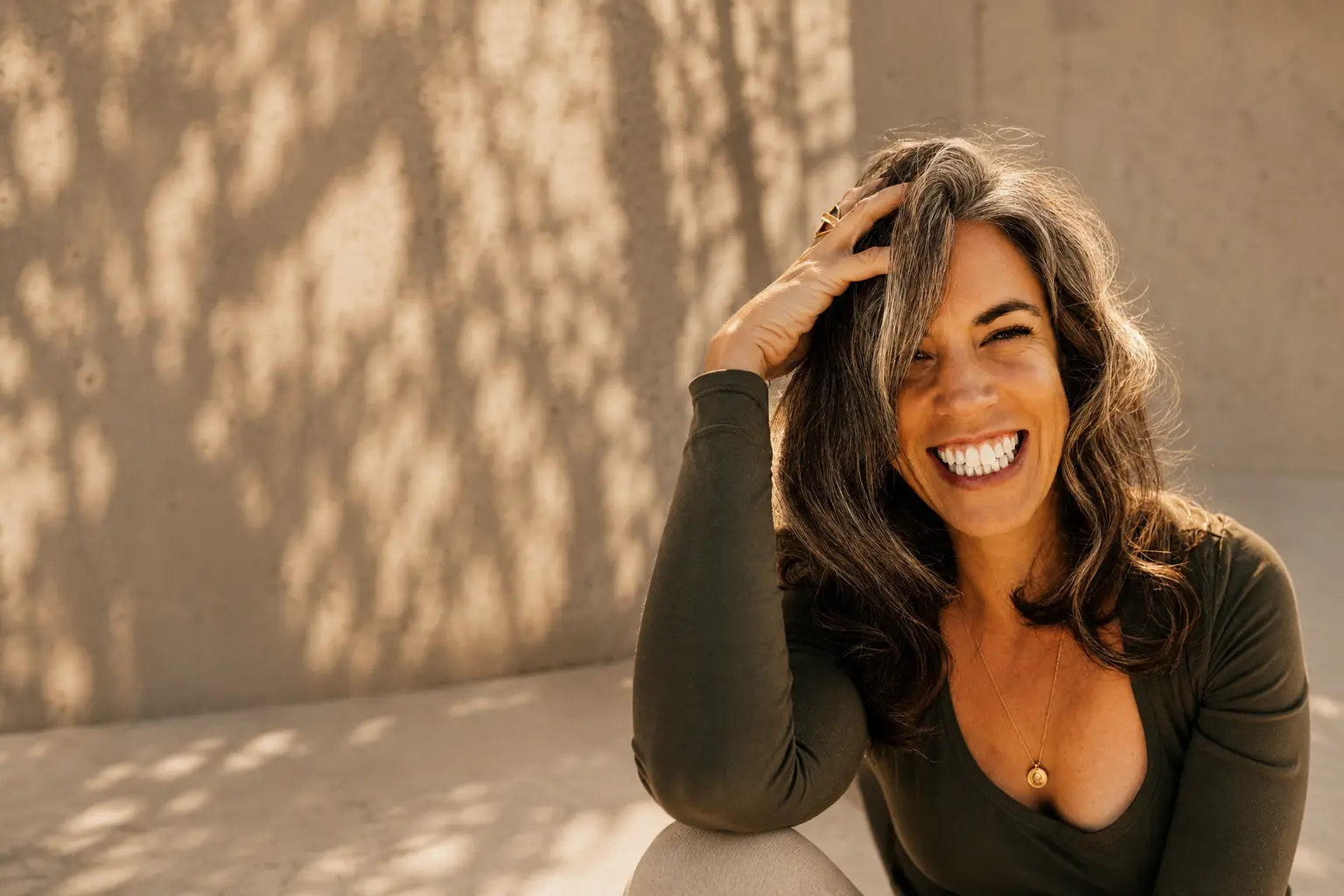 Marla Moffet laughing in warm afternoon light against a sunlit concrete wall